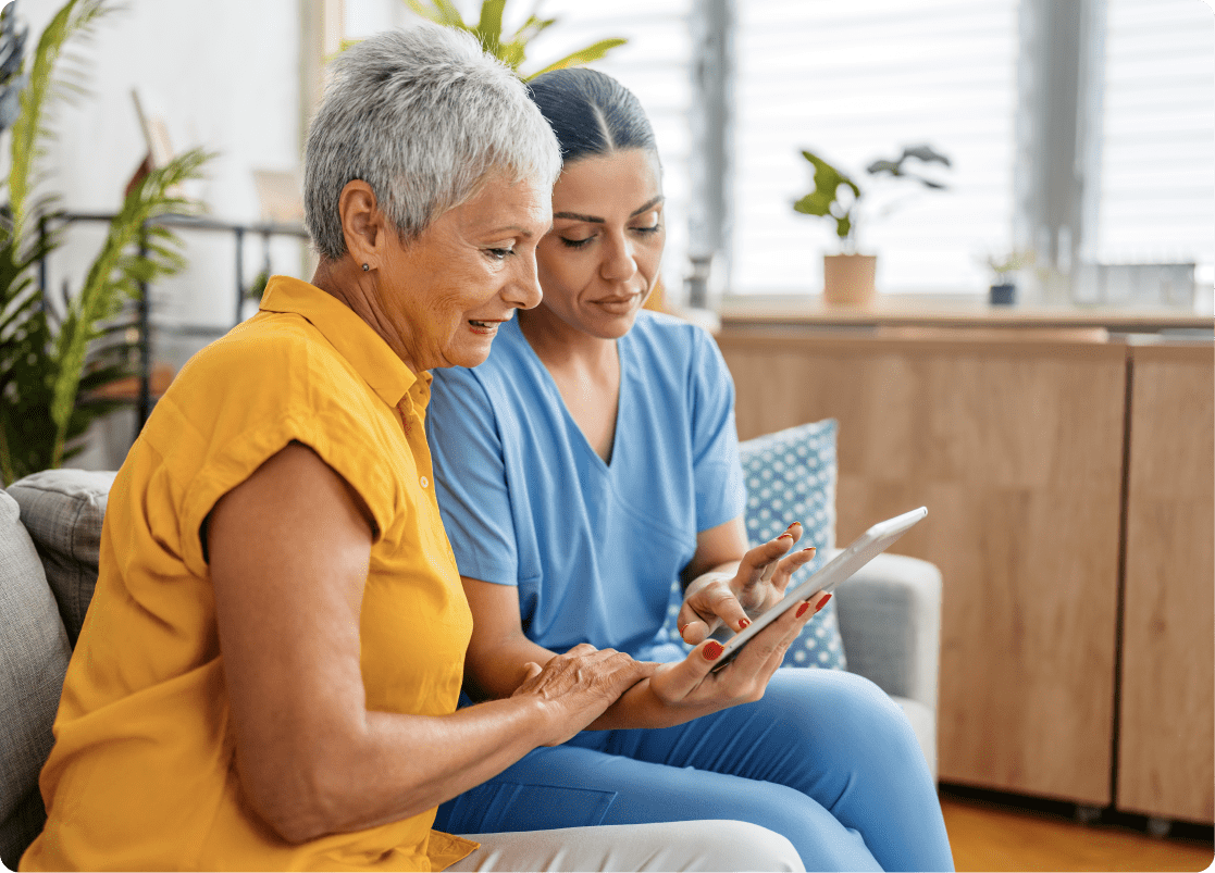 Nurse providing patient education using a digital tablet with an older woman.