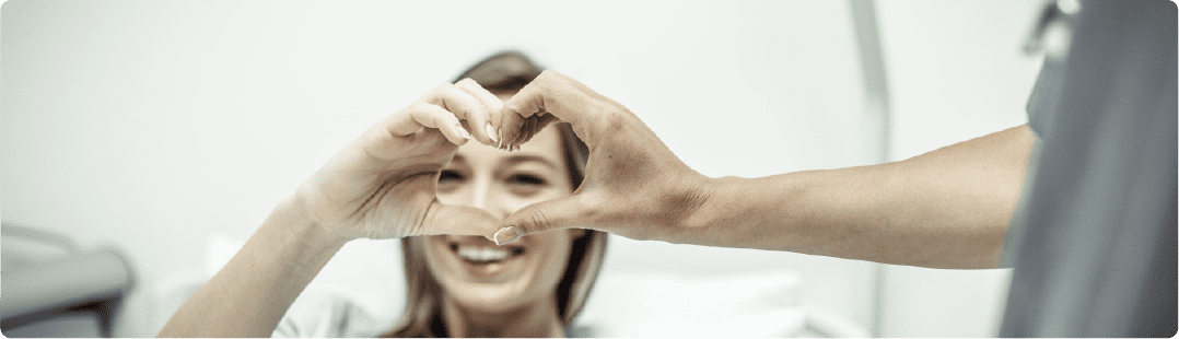 A patitent is doing her fingers like a heart with her doctors as a symbol of patient satisfaction
